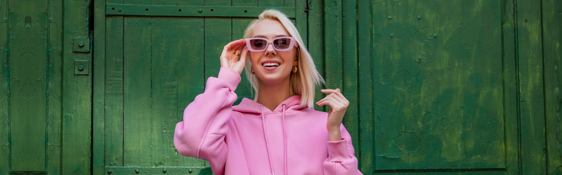 smiling woman wearing a pink hoodie and a sunglasses